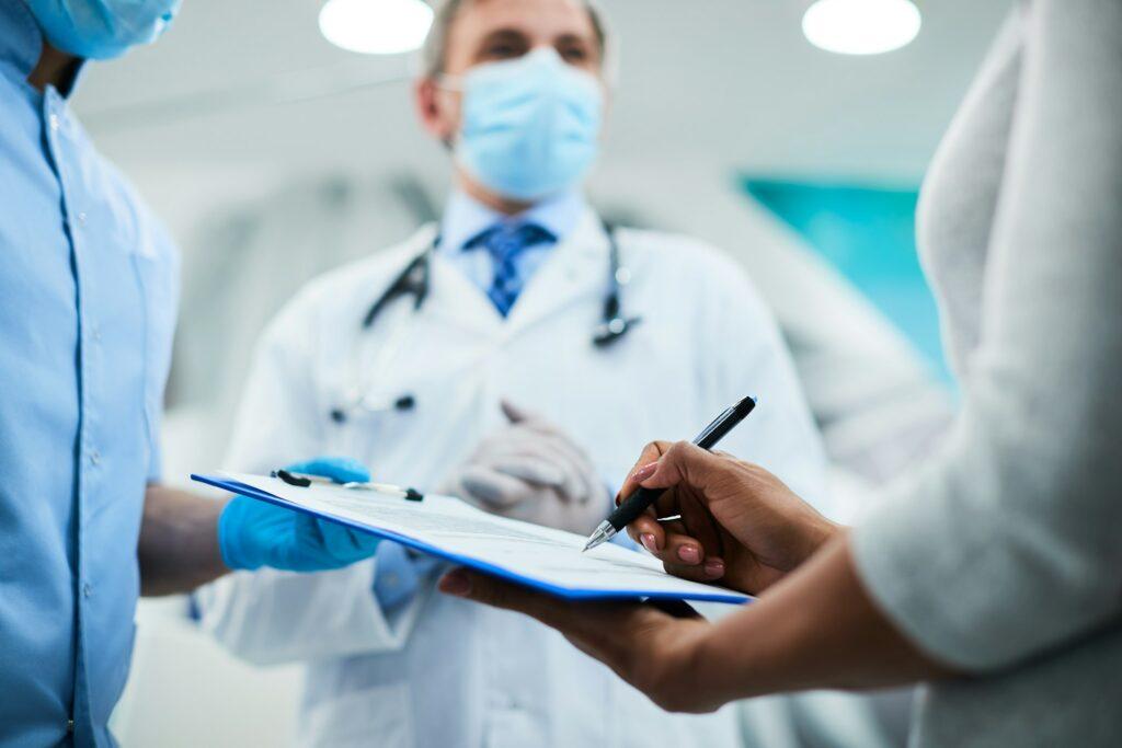 three medical professionals reviewing a document on a clipboard