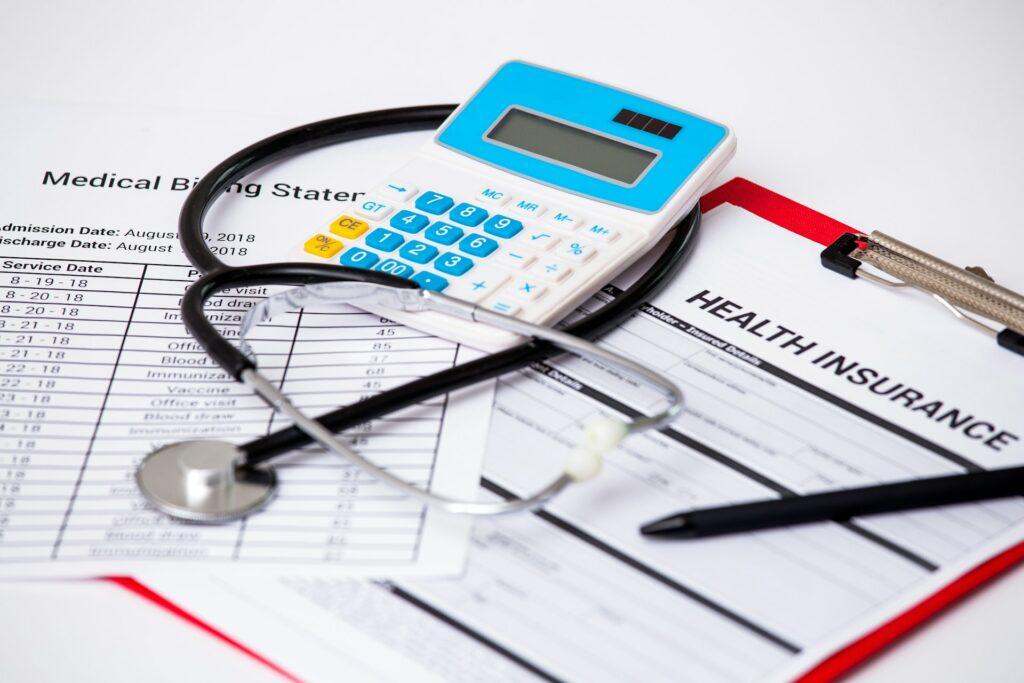 closeup of a calculator, stethoscope, clipboard, and pen