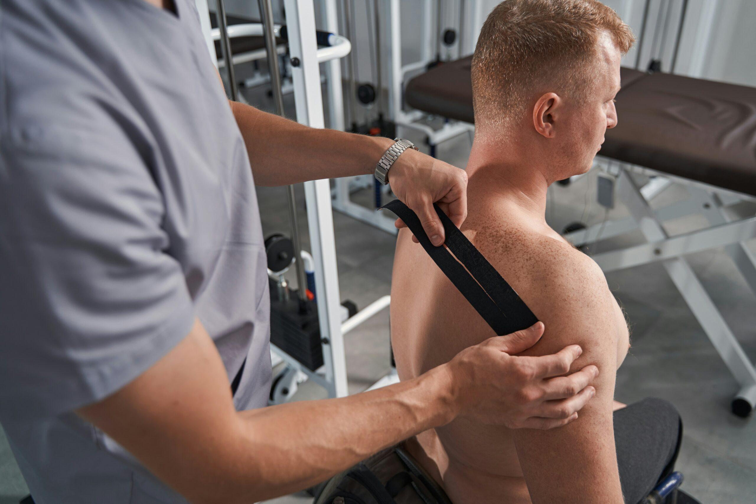a shirtless man being examined by a physical therapist