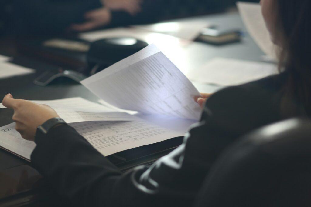 closeup of a person wearing a suit organizing paper documents