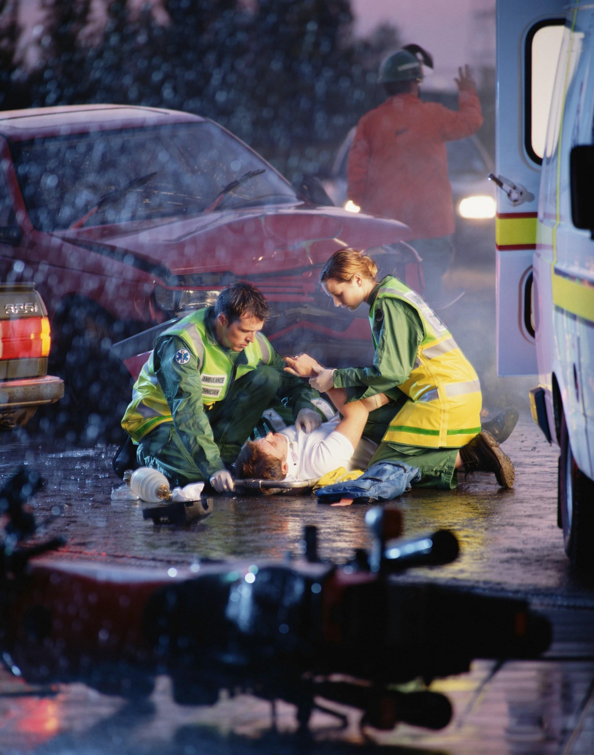paramedics attend to an injured man in the rain