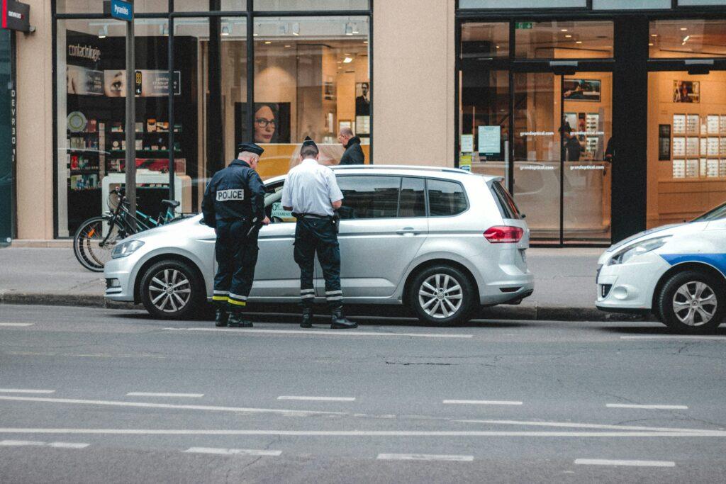 two police officers standing in front of a parked car