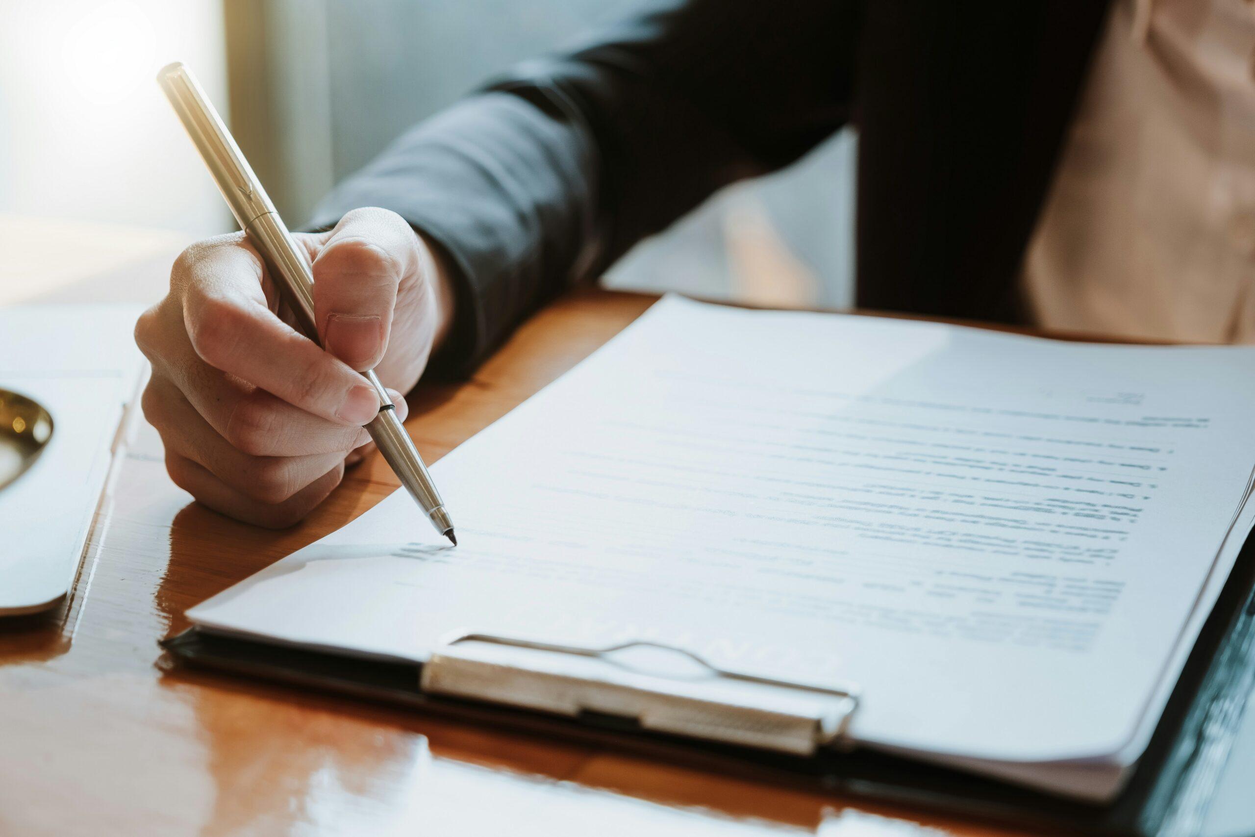 A woman reviews her settlement offer. She has a pen in her hand, ready to sign.