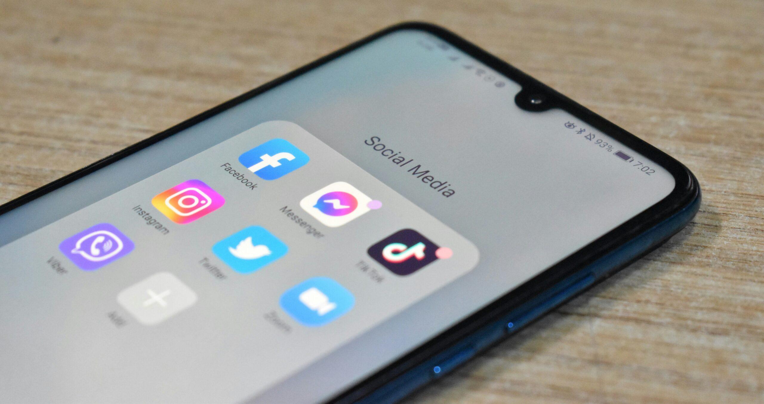 a smartphone on a brown surface. the screen is displaying multiple social media icons