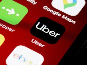 A smartphone screen with the Uber app prominently displayed on a maroon wallpaper.