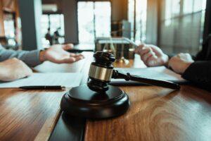 Lawyer and judge at a table with a gavel, discussing a wrongful death settlement case.