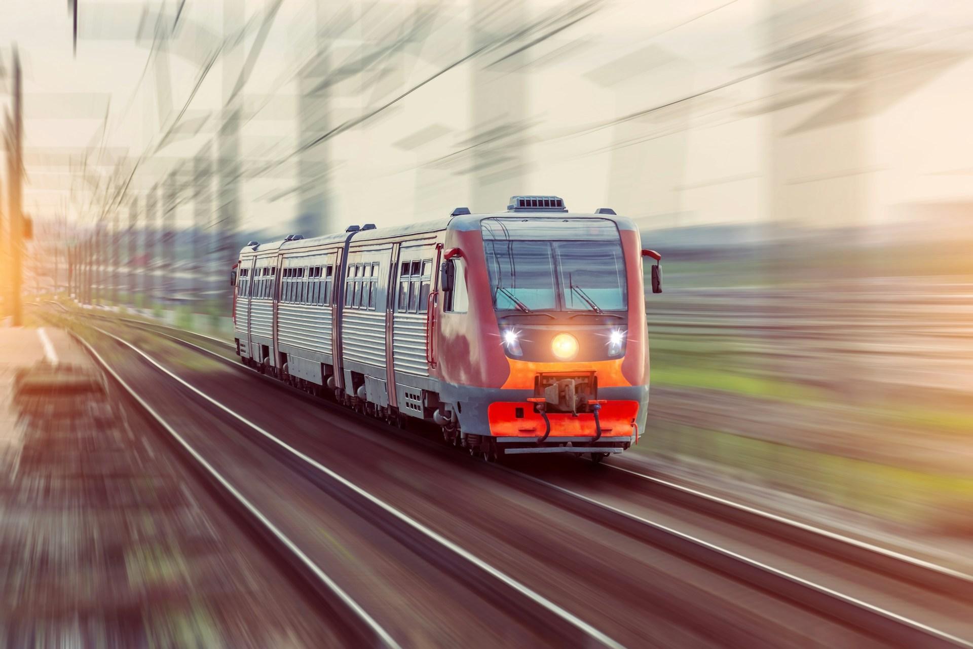 A blurry image of a train moving swiftly along the tracks, emphasizing its speed and motion.