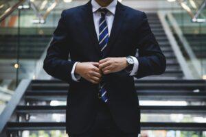 A man in a suit and tie stands confidently on a staircase, exuding professionalism and poise.